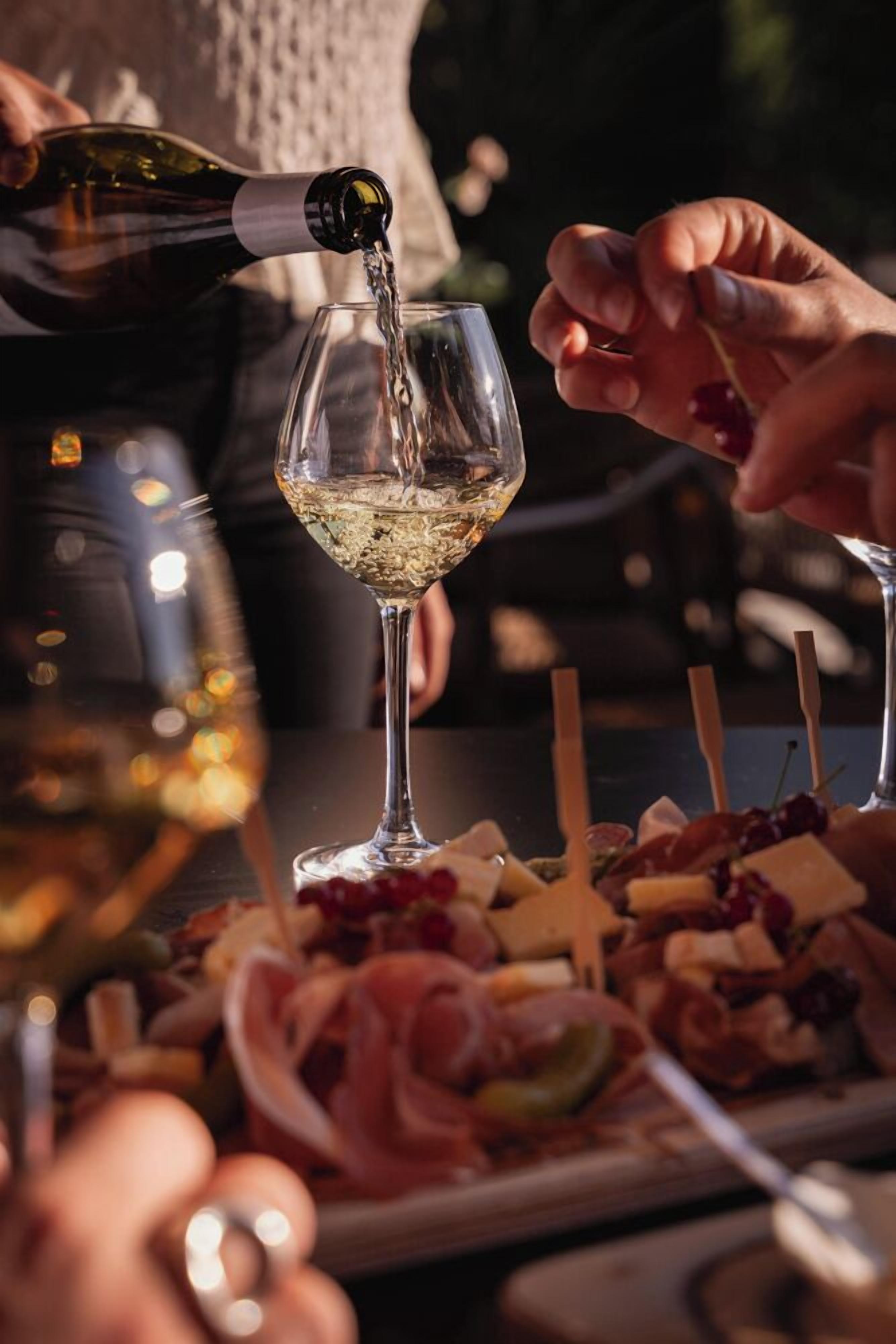 A person pouring wine into a glass.