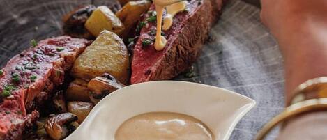 Bife com molho cremoso e batatas assadas em um prato.