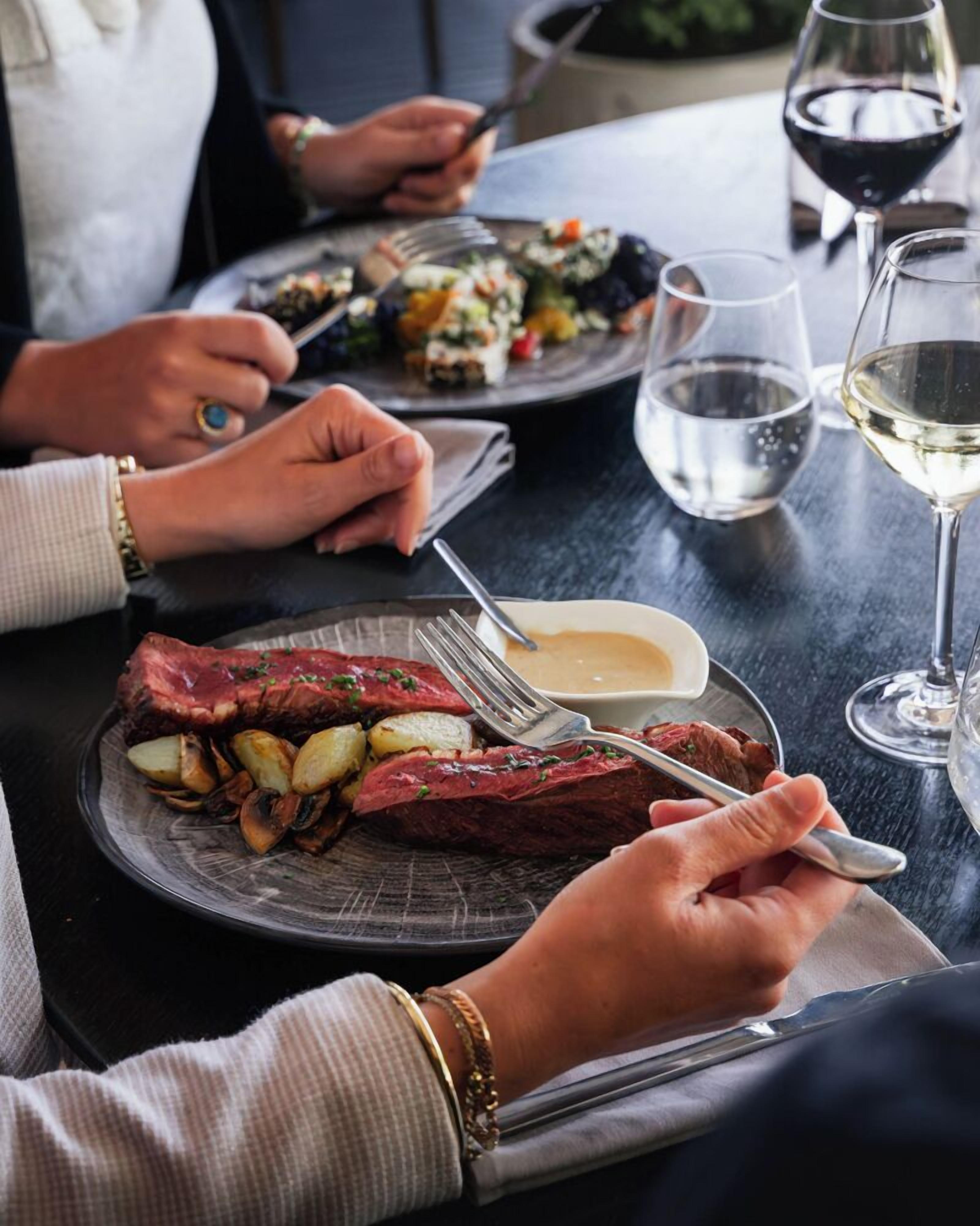 Une table à manger avec des assiettes remplies de nourriture, des verres à vin et des couverts.