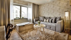 A living room with a sofa, ottoman, round table, and a chair. - Corner Hotel (Stockholm)