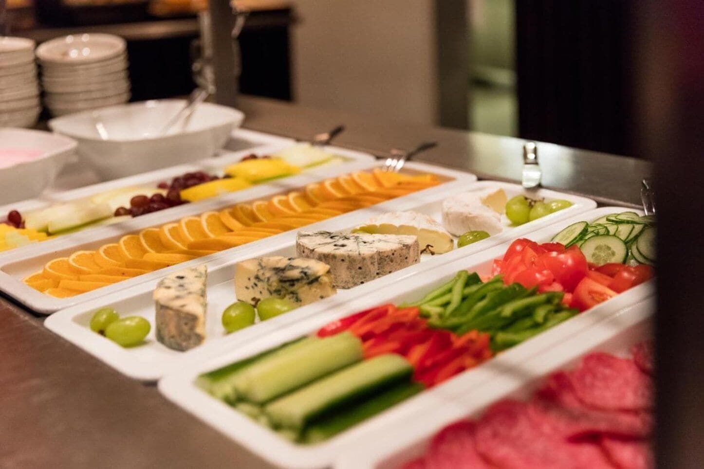 A buffet with various food items including fruits, cheeses, and vegetables.