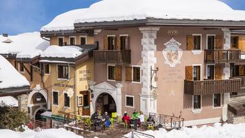 Classic European hotel with a central entrance and symmetrical facade, featuring wooden shutters and balconies.