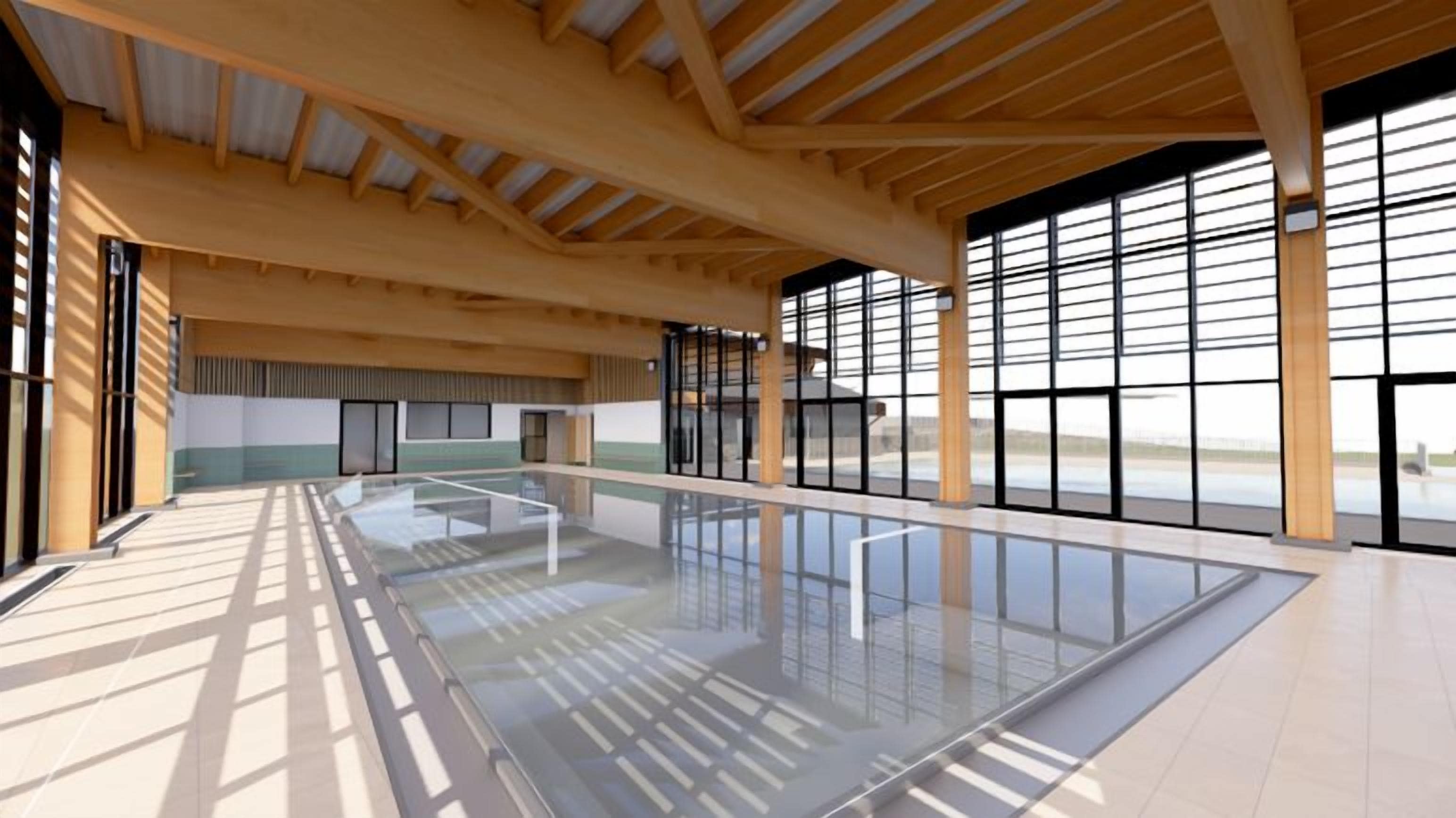 Une piscine intérieure spacieuse, dotée d’un haut plafond et de grandes fenêtres.