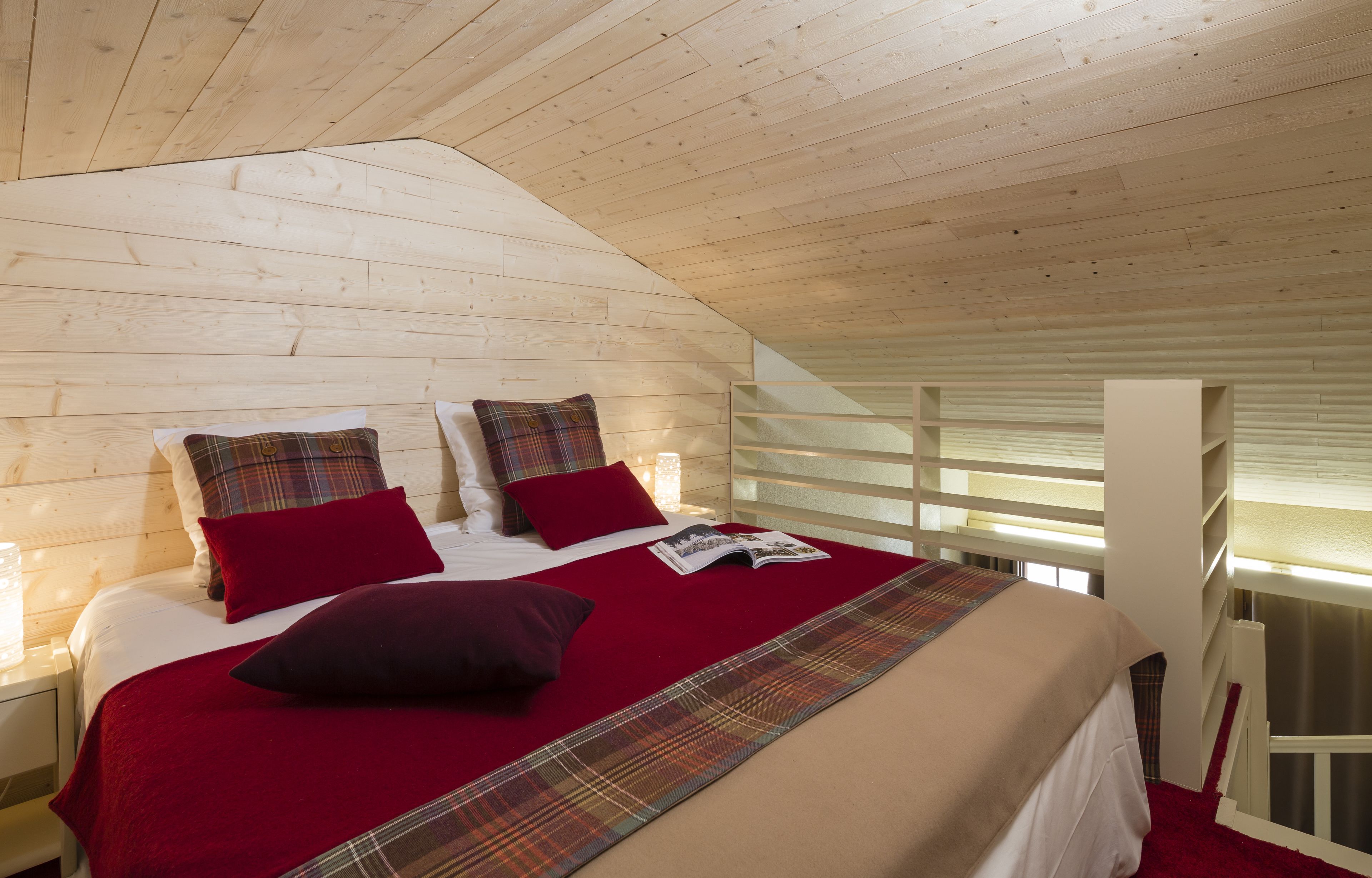 A wooden cabin bedroom with a bed, pillows, and a magazine.