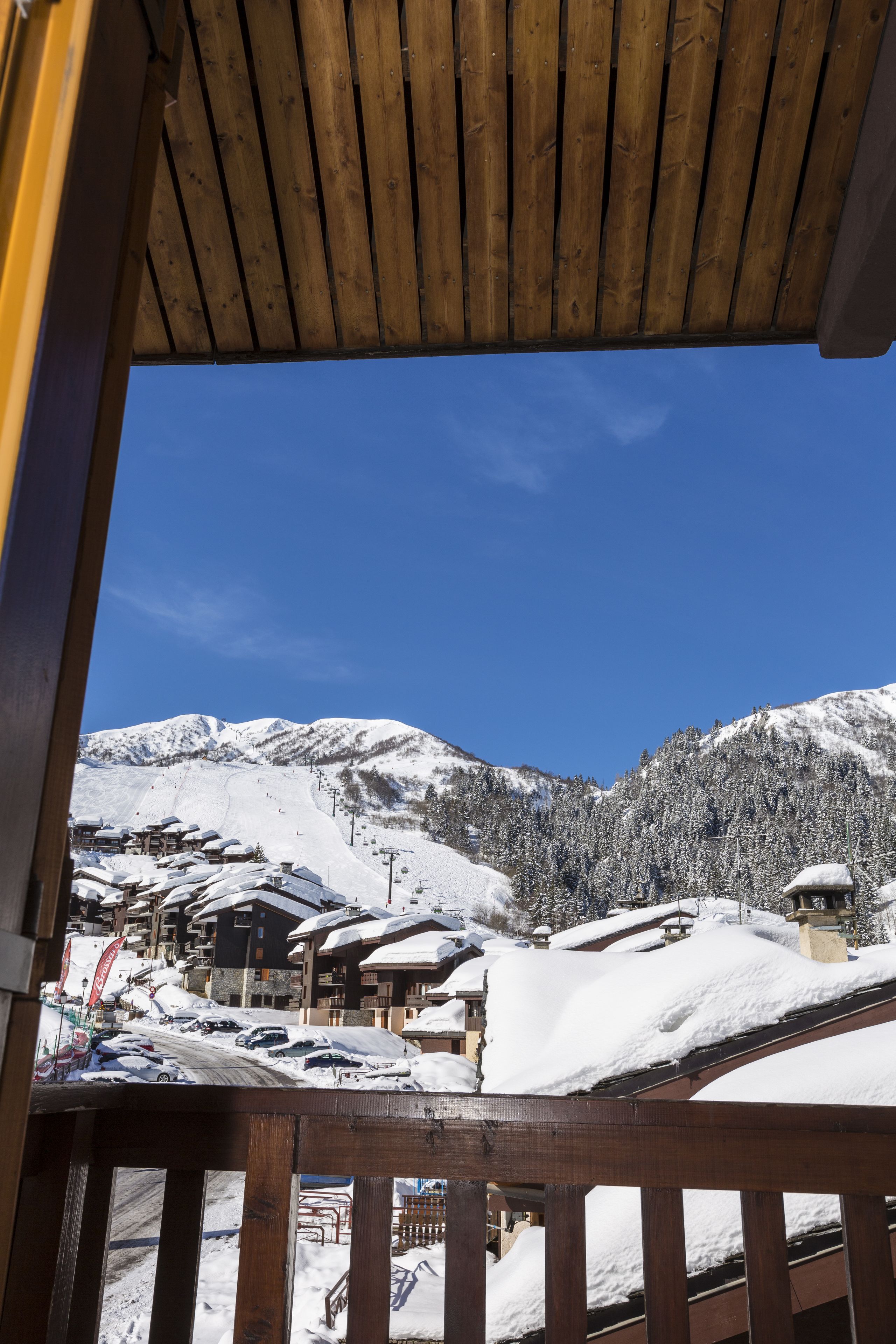 Ein verschneites Bergdorf mit Holzhäusern und blauem Himmel.