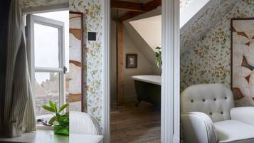 A room with floral wallpaper, a dining table with a chair, a green plant, and a framed artwork on the wall.
