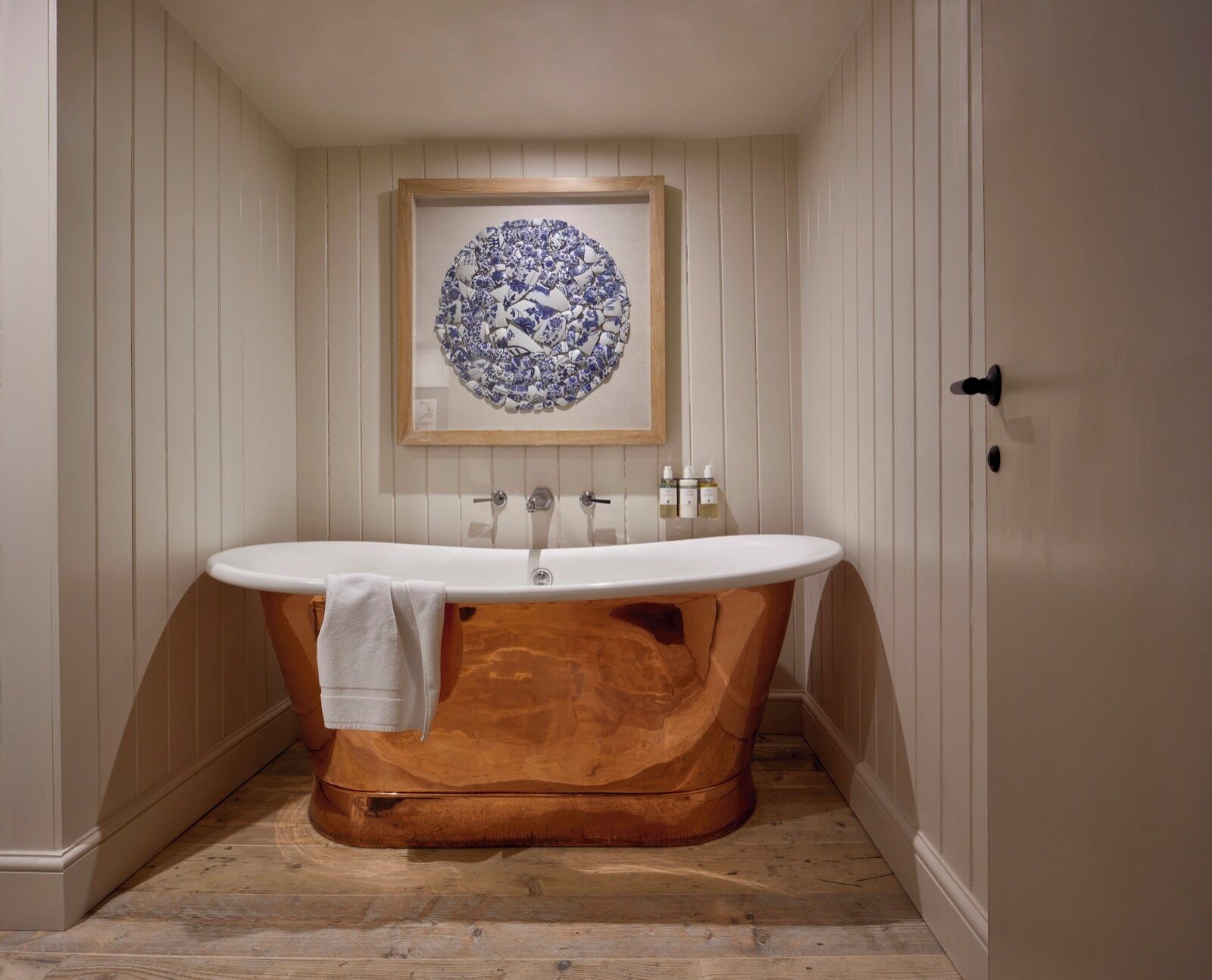 Une salle de bain avec une baignoire sur pieds, un meuble-lavabo en bois et un lavabo fixé au mur.