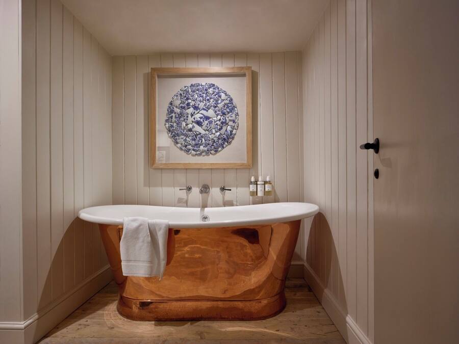 Une salle de bain avec une baignoire sur pieds, un meuble-lavabo en bois et un lavabo fixé au mur.
