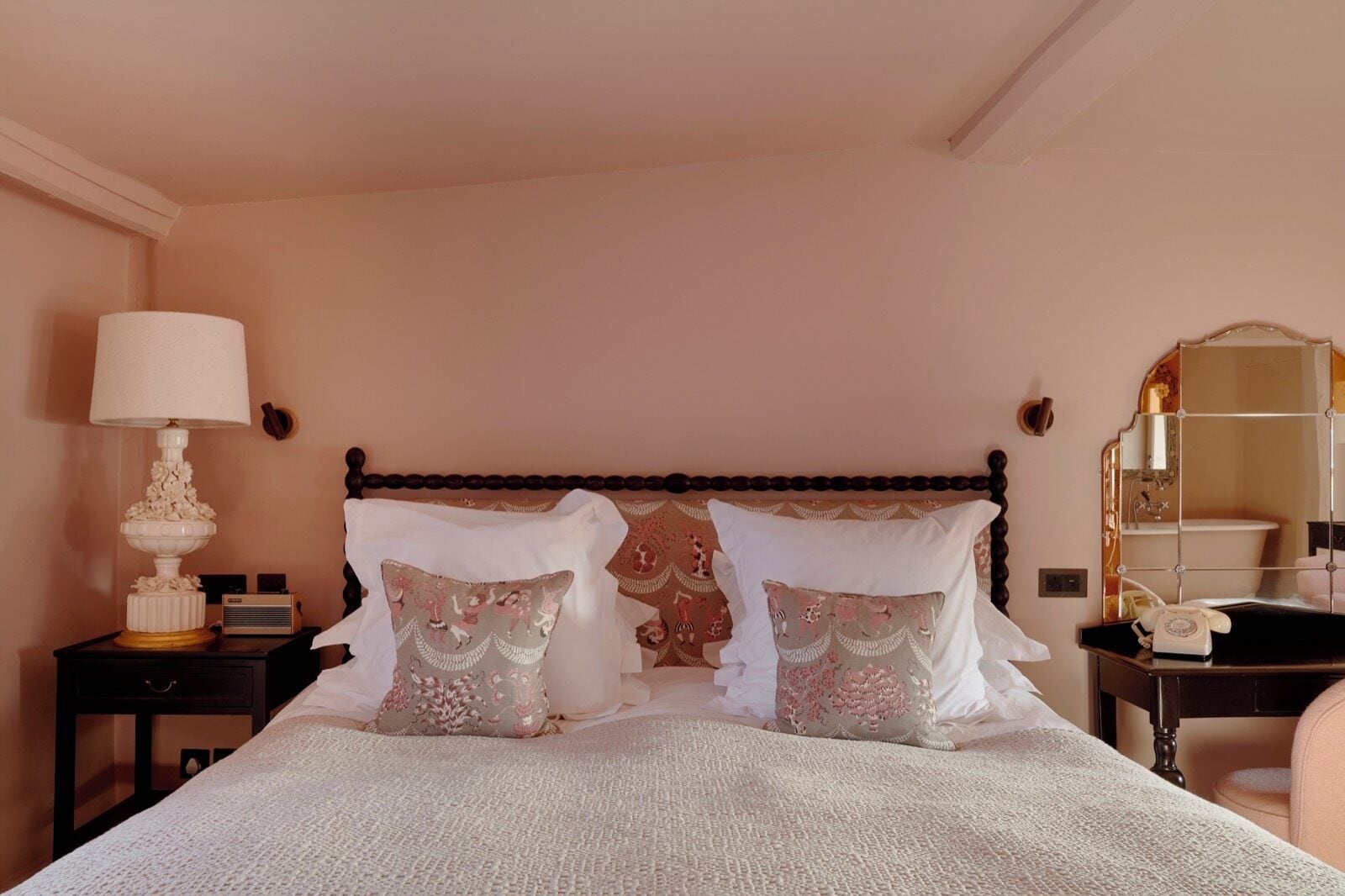 A bedroom with a bed, two nightstands, a lamp, a telephone, and a mirror.