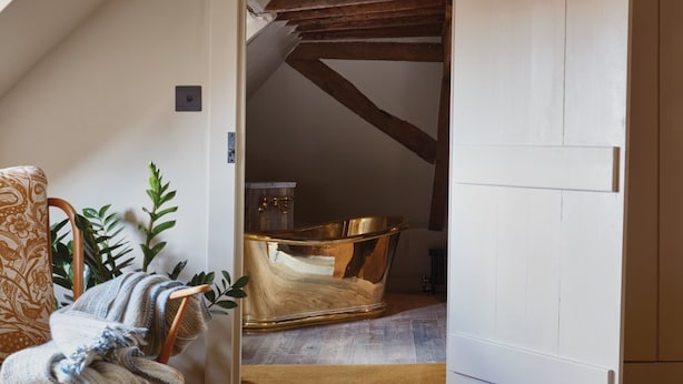 A room with a wooden chair, a large mirror, and a bathtub.
