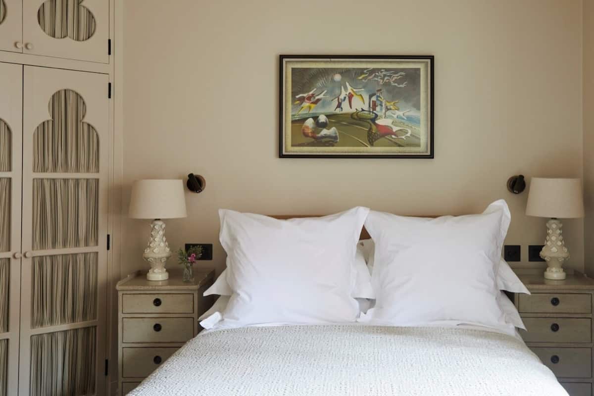 Una cama bien hecha con dos almohadas y dos mesitas de noche con lámparas.