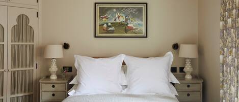 A neatly made bed with two pillows and two bedside tables with lamps.