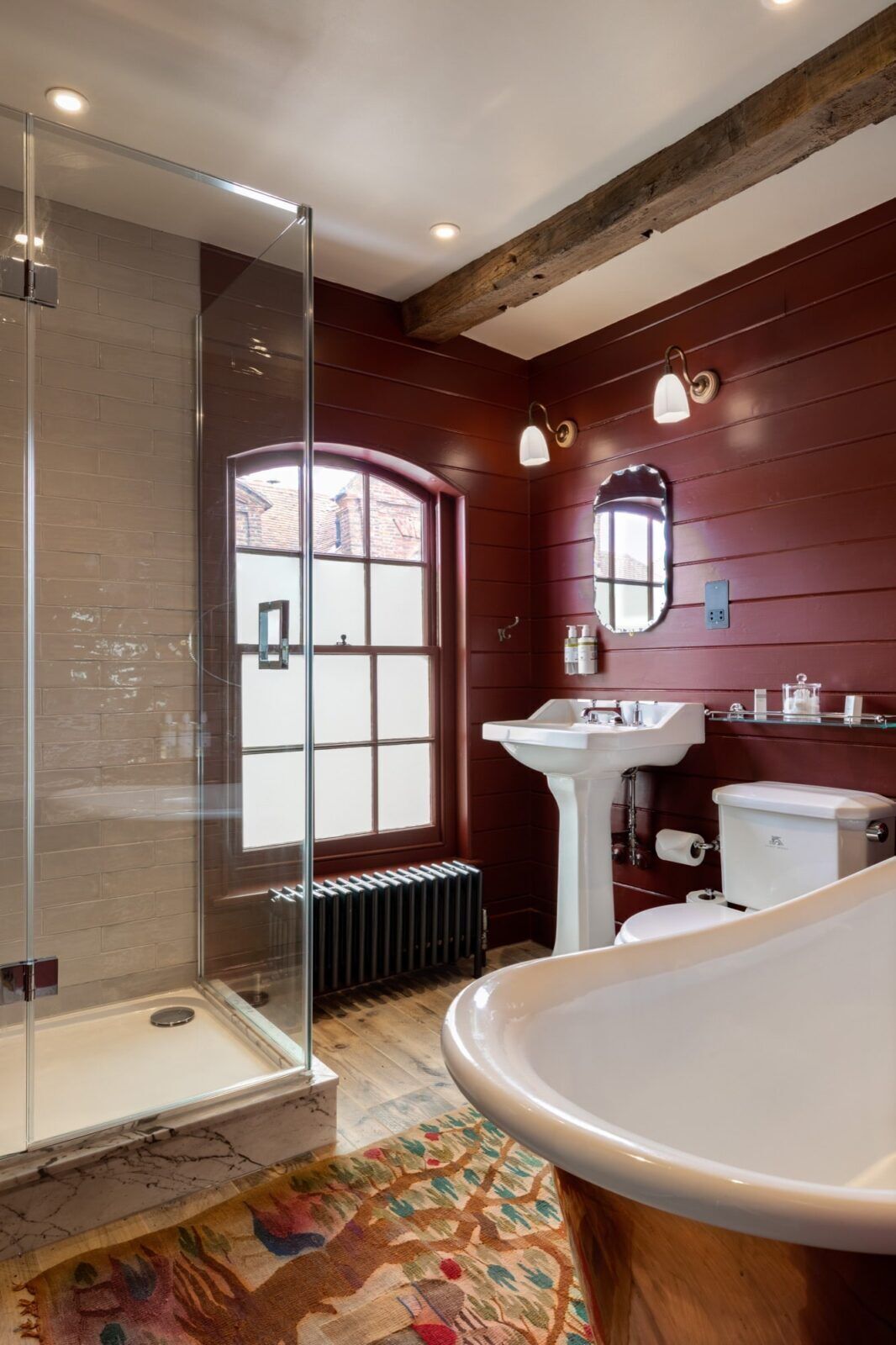 A bathroom with a glass shower enclosure, a large bathtub, a white sink, and a toilet.