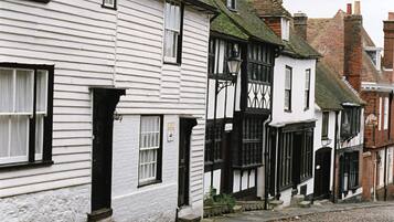 A row of traditional white buildings with black window frames and a cobblestone street.