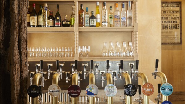 A bar area with multiple liquor bottles and a variety of beer taps.