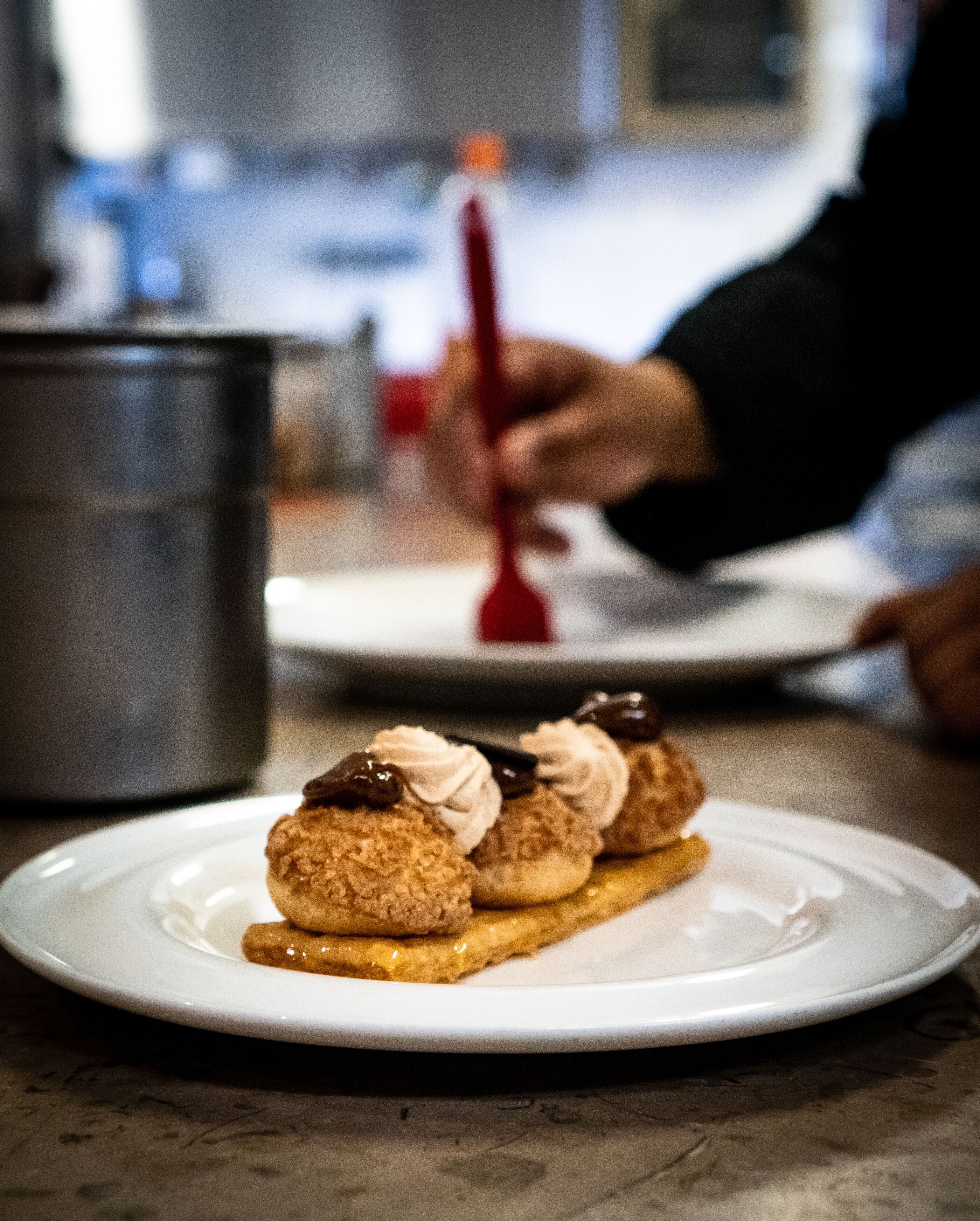 A dessert on a white plate with a metal pot in the background.