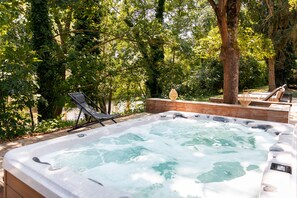 A hot tub surrounded by trees, with lounge chairs and a wooden deck. - Hôtel Diana Restaurant & Spa by Happyculture (Molsheim)