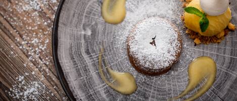 A dessert on a plate with powdered sugar and a mint leaf.