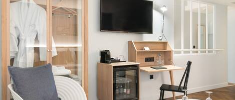 Une chambre d’hôtel moderne dotée d’un coin salon, d’une télévision, d’un minibar et d’un grand miroir.