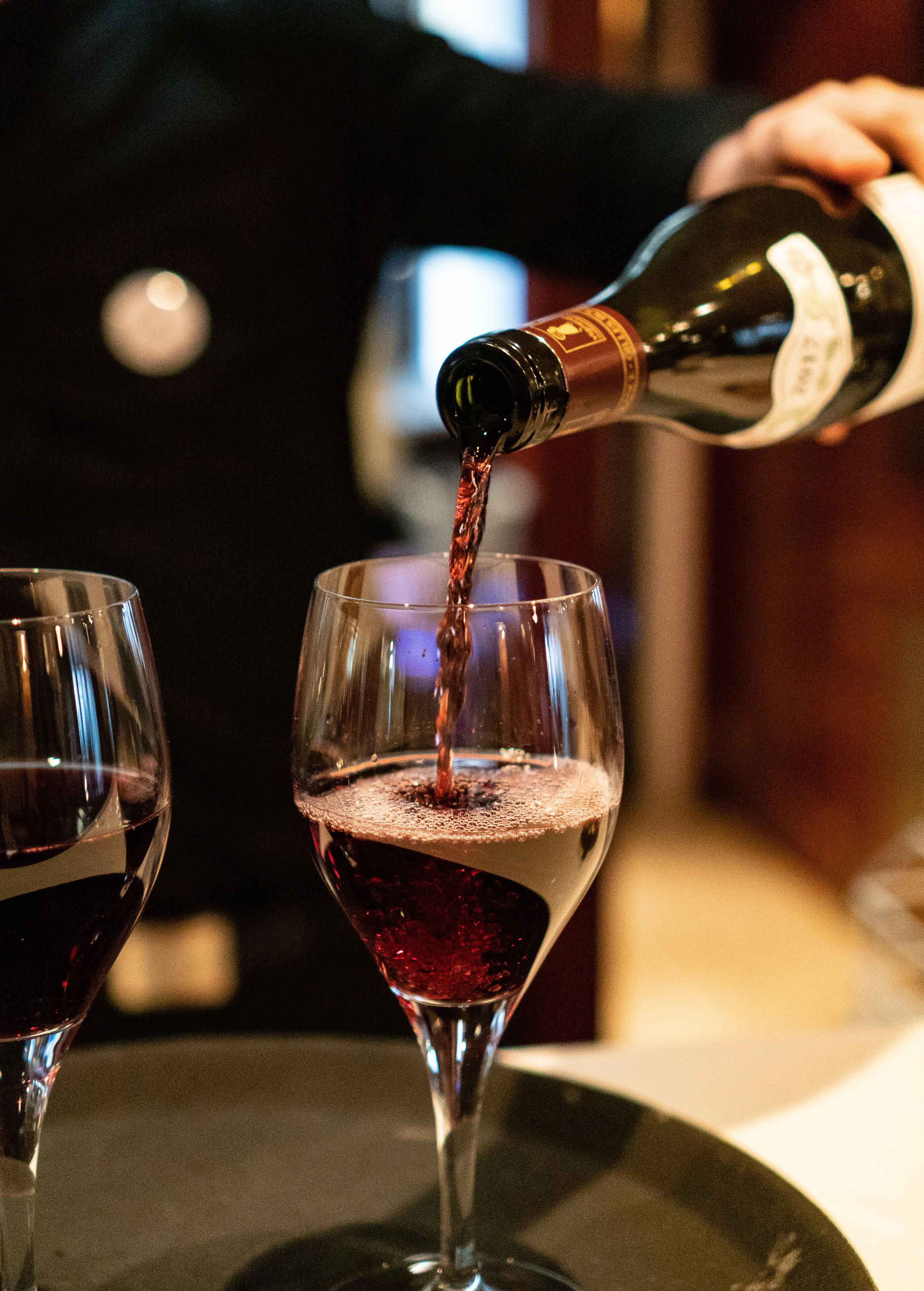 On verse du vin rouge d’une bouteille dans un verre à vin.