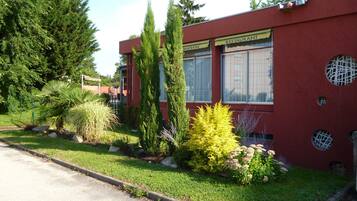 Un bâtiment rouge avec une enseigne indiquant « RESTAURANT », entouré de différentes plantes et arbres.