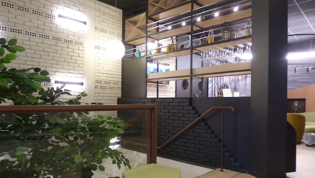 A modern interior with a staircase, a glass railing, and a plant.