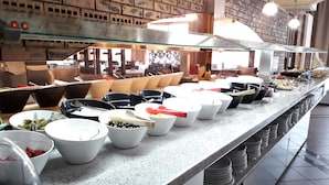A buffet setup with various food items and bowls on a granite countertop.