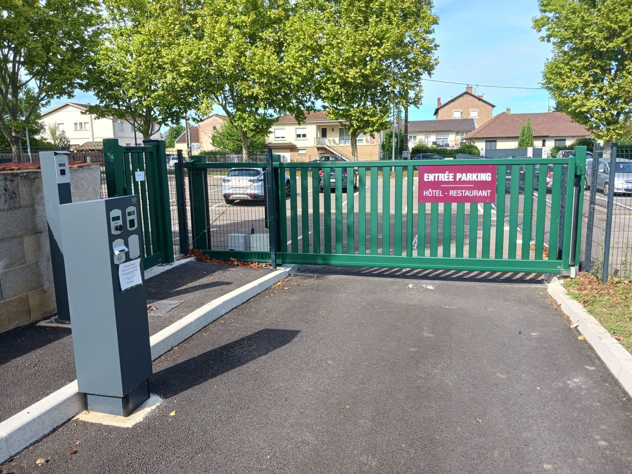 A gated entrance to a parking area with a sign indicating it leads to a hotel and restaurant.
