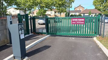 A gated entrance to a parking area with a sign indicating it leads to a hotel and restaurant.
