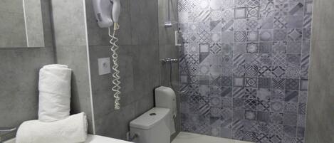 A bathroom with a white sink, toilet, and shower with patterned tiles.