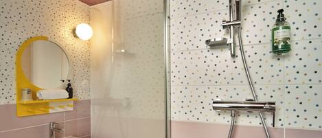 A bathroom with a sink, mirror, shower, and tiled walls.