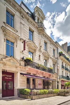 A historic building with ornate architecture, including a prominent Artyster sign, a balcony with plants, and a visible restaurant sign. - The Originals City, Hôtel Artyster, Le Mans Centre (Le Mans)