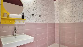 A bathroom with a white sink, a yellow vanity with a mirror, and pink tiled walls.