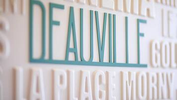 A close-up of a wall with various words in different fonts and colors, including "DEAUVILLE" prominently displayed.