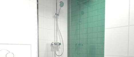 Un baño moderno con ducha envuelta en vidrio, paredes de azulejos blancos y un inodoro.