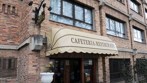 A brick building with a cafe/restaurant sign. - Hotel Corregidor (Segovia)
