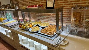 A buffet counter with various food items, including fruits, pastries, and beverages. - Hotel Corregidor (Segovia)