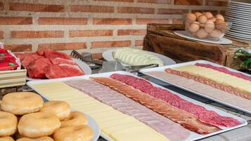 Una mesa de buffet con diversas opciones de comida, como carnes, quesos y pasteles.