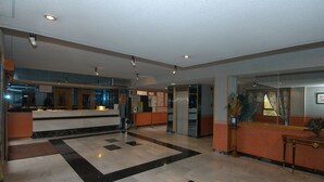 A hotel lobby with a reception desk, a check-in counter, and a seating area with a plant. - Hotel Corregidor (Segovia)