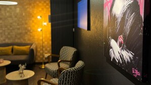 A modern lounge area with a sofa, chairs, and a coffee table. A large poster is displayed on the wall.