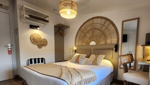 A spacious bedroom with a large bed, a round woven headboard, a bedside table, and a chair.