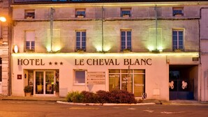A hotel named "HOTEL LE CHEVAL BLANC" with a signboard indicating services like "CLIMATISE" and "TERASSE".