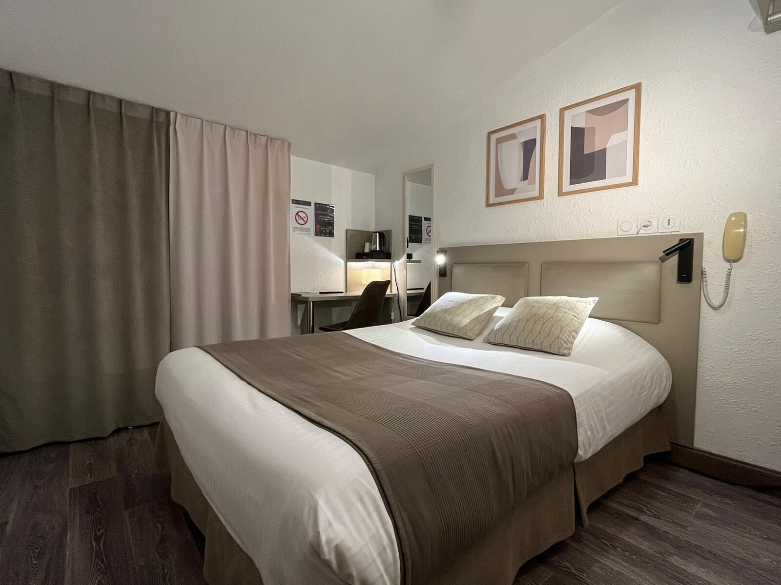 Una habitación de hotel con una cama grande, un escritorio y un teléfono.