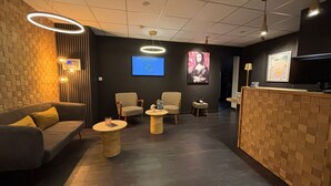 A modern lobby with a reception desk, seating area, and a television screen.