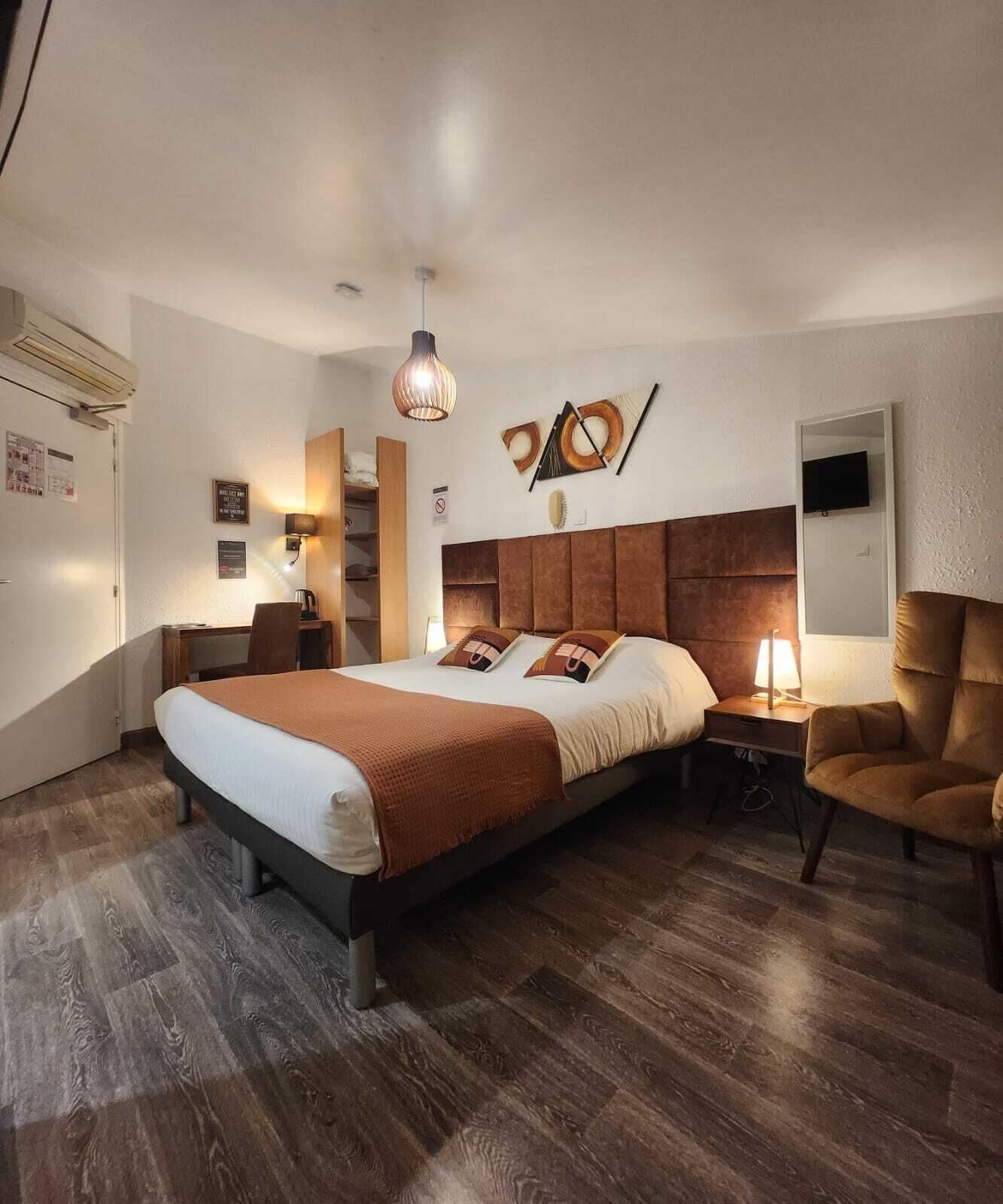 Habitación de hotel con una cama grande, mesitas de noche, un escritorio, una silla, un televisor y una obra de arte colgada en la pared.