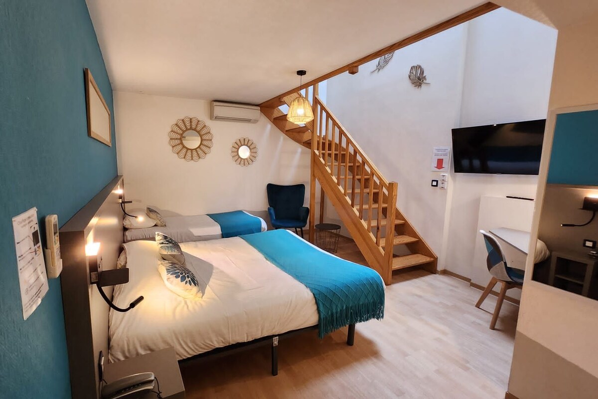 Un dormitorio con cama, escritorio, silla, escalera y televisor.
