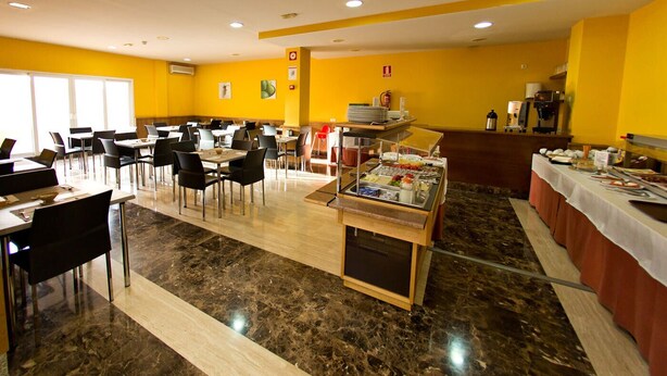 A spacious dining area with multiple tables and chairs, a buffet station, and a coffee machine. - Hostal San Marcos (San Martin de la Vega)