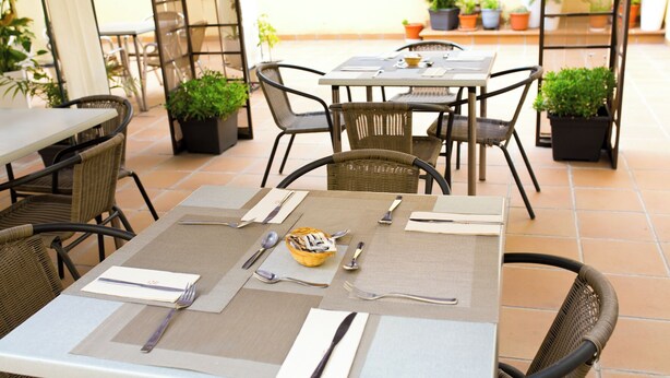 An outdoor patio with tables and chairs, some with plants. - Hostal San Marcos (San Martin de la Vega)