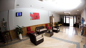 A spacious lobby with a wooden floor, a large red flower painting, and a television mounted on the wall. - Hostal San Marcos (San Martin de la Vega)