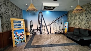 A room with a roller coaster mural, a buffet sign, a couch, and a wooden floor. - Hostal San Marcos (San Martin de la Vega)